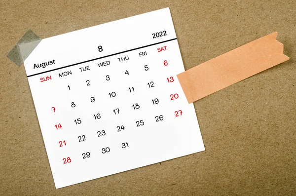 2022年8月のカレンダーには 茶色の背景に空白の接着剤ノート紙があります — ストック写真