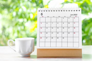 Doğa arka planındaki ahşap masa üzerinde planlama ve hatırlatma için Haziran 2022 Takvim masası.