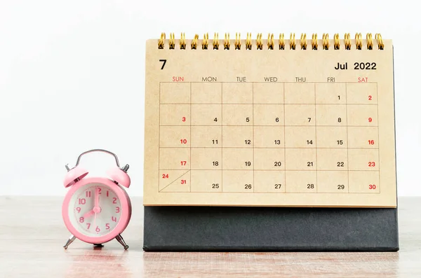 Schreibtischkalender Juli 2022 Mit Pinkfarbenem Wecker Auf Holztisch — Stockfoto