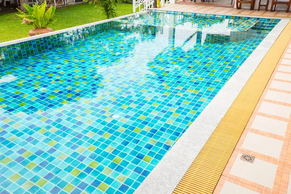 Yüzme havuzunun Macro 'su. Bahçe bölgesinde, bitkilerle çevrili berrak mavi bir su var.