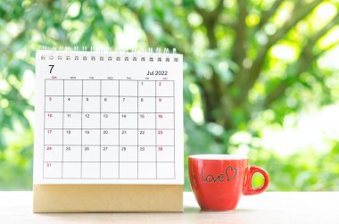 Organizatörün, doğanın arka planındaki ahşap masa üzerinde planlaması ve hatırlatması için Temmuz 2022 takvim masası..