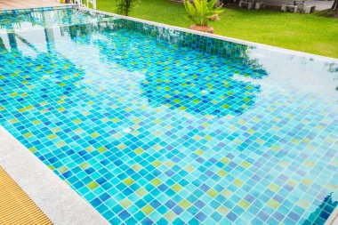 Yüzme havuzunun Macro 'su. Bahçe bölgesinde, bitkilerle çevrili berrak mavi bir su var.