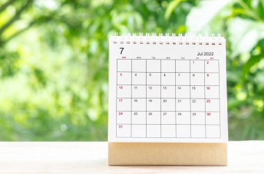 Organizatörün, doğanın arka planındaki ahşap masa üzerinde planlaması ve hatırlatması için Temmuz 2022 takvim masası..