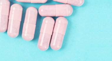 Mavi arka planda Pembe kapsül hapları.