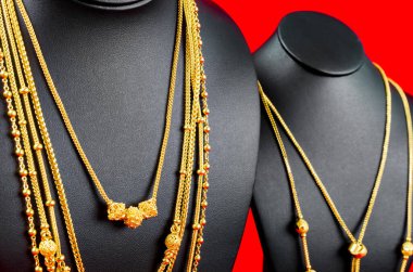 Kolye standını kırmızı kadife kumaşın üzerinde altın kolyeyle kapat..