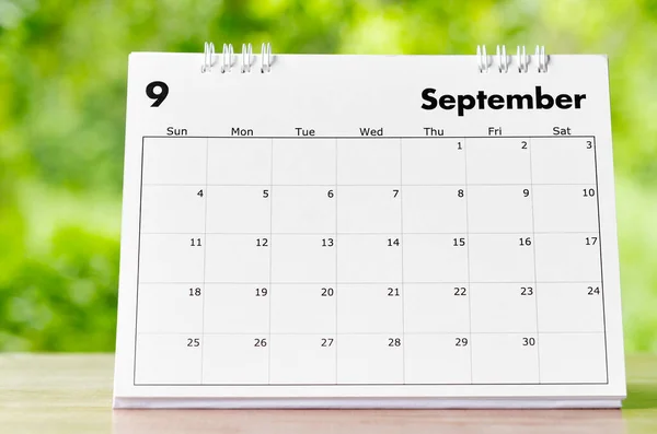 The September 2022 Calendar desk for organizer to plan and reminder on wooden table on nature background.