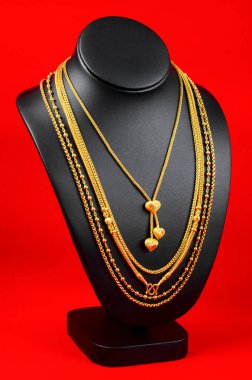 Kolye standı kırmızı kadife kumaşın üzerinde altın kolyeyle.