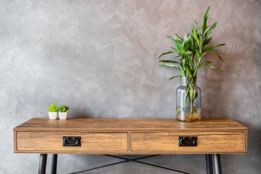 Beton duvarda saksı olan boş ahşap masa mahsulü.