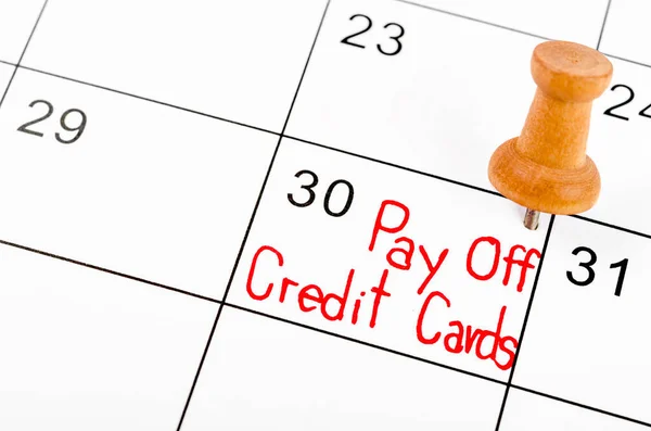 Words Pay off Credit Cards written on a Calendar with wooden pin.