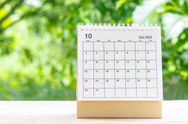 October 2022 Calendar desk for organizer to plan and reminder on wooden table on nature background.