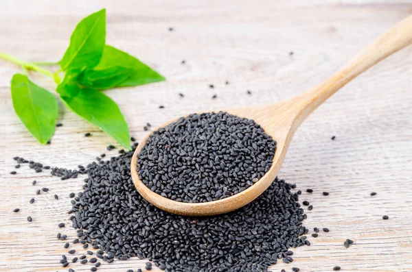 A Spoon full hoary basil seed on pile of hoary basil seed on wooden background.