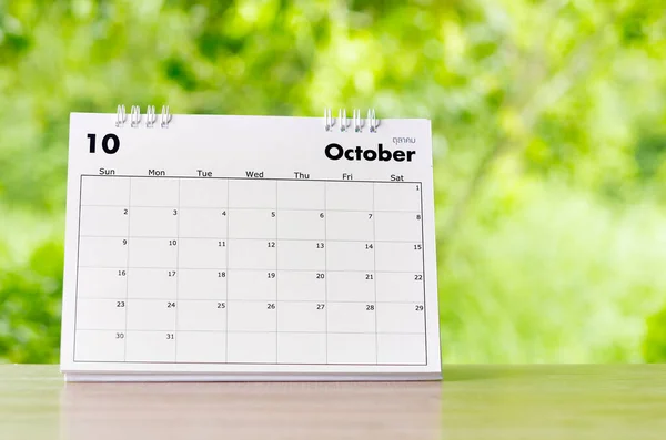 October 2022 Calendar desk for organizer to plan and reminder on wooden table on nature background.