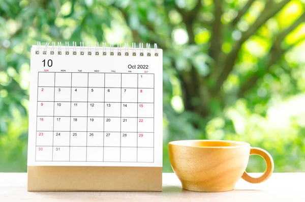 October 2022 Calendar desk for organizer to plan and reminder on wooden table on nature background.