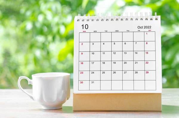 October 2022 Calendar desk for organizer to plan and reminder on wooden table on nature background.