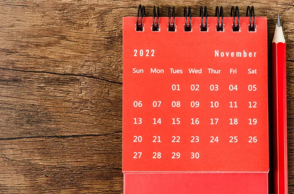 Red November 2022 Monthly desk calendar for 2022 year with red pencil on wooden background.