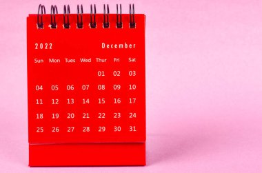 Pembe arka planda 2022 yılı için Kırmızı Aralık 2022 Aylık masa takvimi.