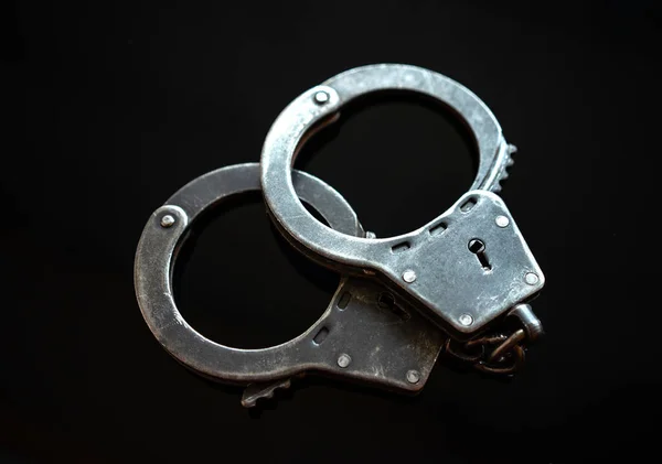 Police metal handcuffs on black isolate. Arrest of the suspect. Criminal news. Restriction of freedom. — Stock Photo, Image