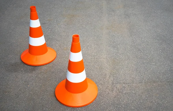 Conos de tráfico naranja en una carretera asfaltada. Antecedentes del texto sobre noticias viales. Aprobando el examen de licencia de auto. Reparaciones anuales de carreteras. — Foto de Stock