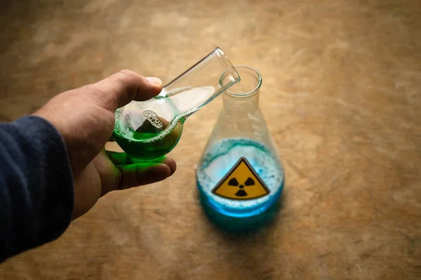 Uma mão derrama líquido radioativo em uma pedra de vidro. Produção de combustível nuclear. — Fotografia de Stock