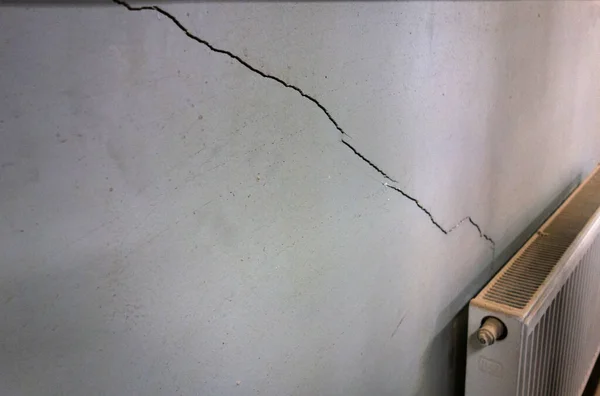 A crack on the wall after an earthquake. The destruction of the wall of the house.Poor-quality repair of the building. — Stock Photo, Image