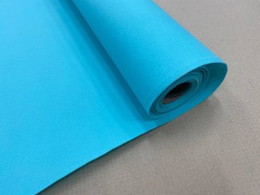 Masanın üzerinde mavi deniz renginde bir keçeli kumaş rulosu.