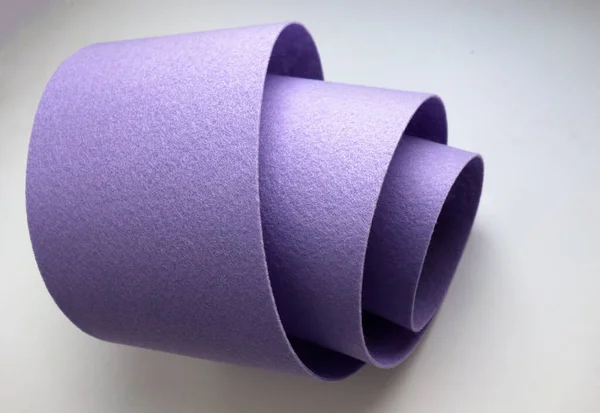 Purple felt is rolled into a tube on a white isolate. Production and sale of felt fabric.Purple fabric for needlework. — Stockfoto