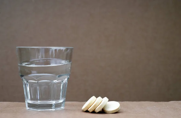 Un vaso de vidrio con agua y tres pastillas de aspirina. Tomando medicamentos. un fondo limpio para el texto. Recetar medicamentos. —  Fotos de Stock