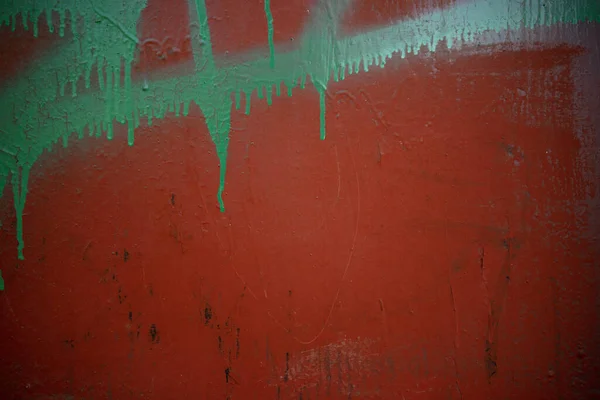 A red street wall with traces of paint from aerosol cans.The texture of the wall of the building with streaks of paint. — Stock Photo, Image
