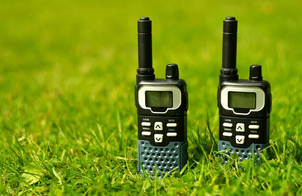 Dwie mobilne krótkofalówki na negocjacje w sprawie zielonej trawy. Instrument negocjacji. — Zdjęcie stockowe