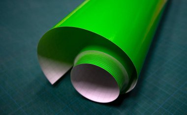A round roll of green vinyl film on the table.