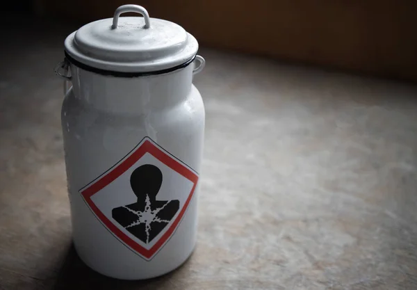 A white jug with a toxic substance . A warning sticker about poisoning on an iron canister. — Zdjęcie stockowe