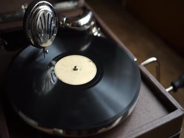 An old gramophone with a handle, twirling a black vinyl record. Retro vinyl record player. — Vídeo de stock