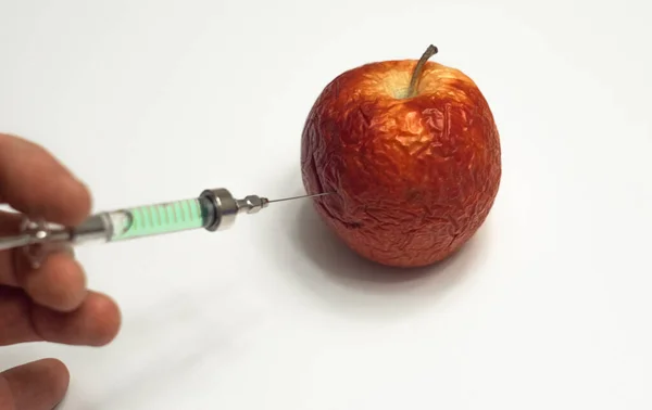 Una inyección de una jeringa en una manzana vieja. Una cura para la vejez. Un remedio para la celulitis. —  Fotos de Stock