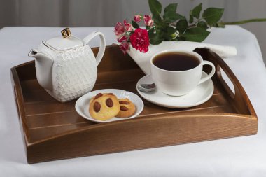 Kurabiyeli bir fincan çay ve tepside bir gül.