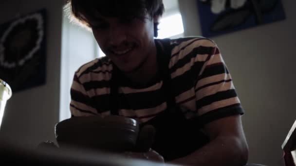 Schieten vanaf het onderste punt van een pottenbakker die aan een pottenbakkerswiel werkt. — Stockvideo