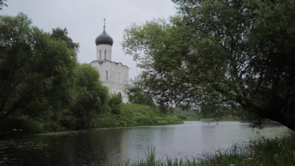 雨の中、貯水池の岸には古代の小さな寺院が立っている。 — ストック動画