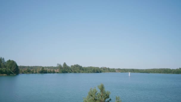 Un voilier blanc navigue sur un petit étang avec de l'eau azur par une journée d'été ensoleillée. — Video