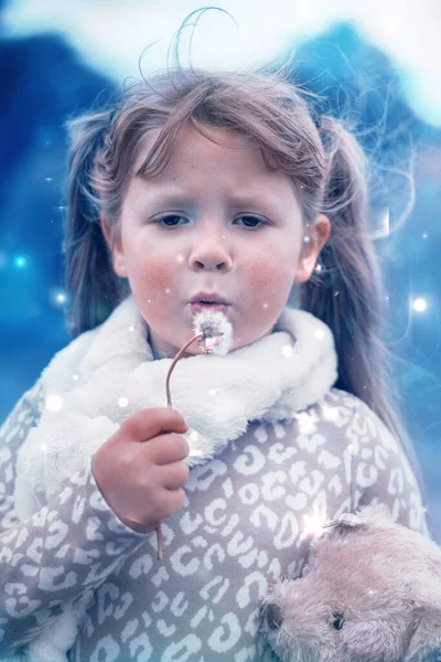 Petite fille soufflant de la neige d'un pissenlit — Photo