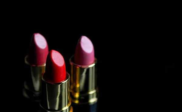 A trio of lipsticks on a black background. — Zdjęcie stockowe