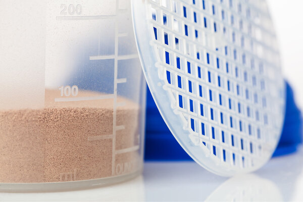 Целый шарик шоколадного сывороточного белка перед протеиновым шейкером и его частями
