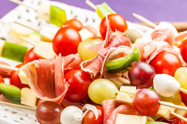 Skewer with grapes, cherry tomatoes, prosciutto and cheese on a — Stock Photo, Image