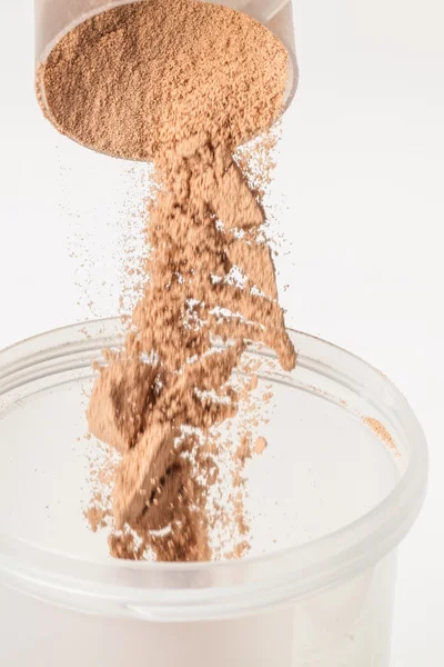 Scoop of chocolate whey isolate protein tossed into plastic whit — Stock Photo, Image