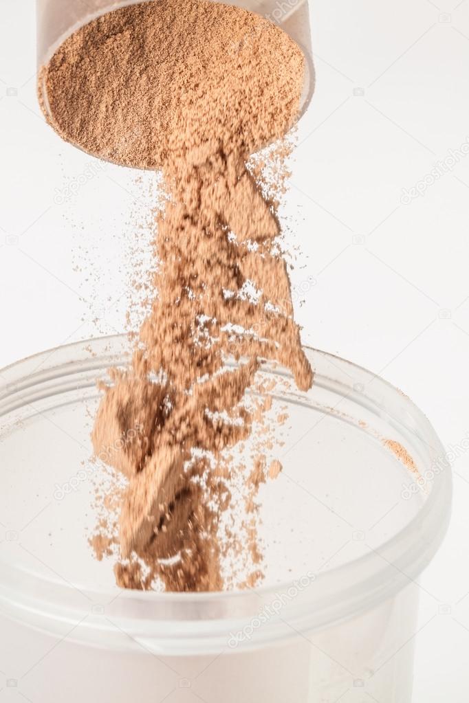 Scoop of chocolate whey isolate protein tossed into plastic whit