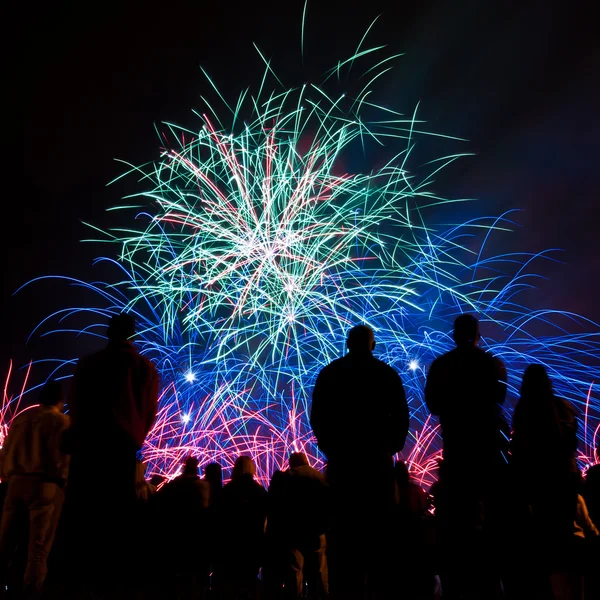 Grandes fuegos artificiales con siluetas de gente mirándolo — Foto de Stock