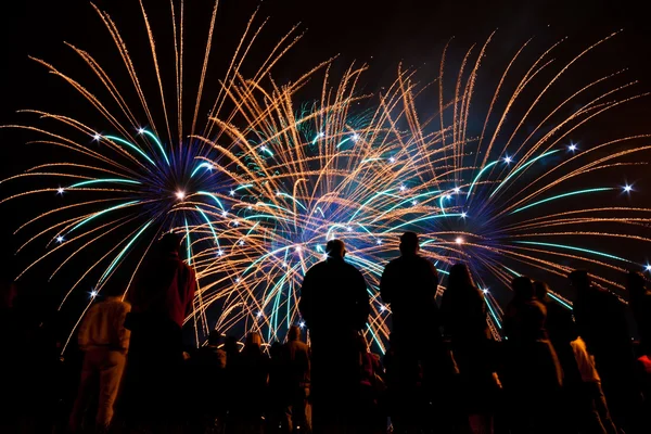 Grandes fuegos artificiales con siluetas de gente mirándolo — Foto de Stock