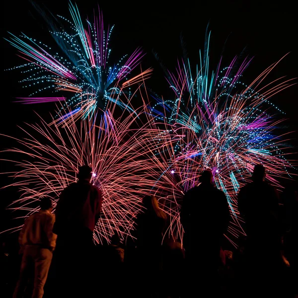 Grandes fuegos artificiales con siluetas de gente mirándolo — Foto de Stock