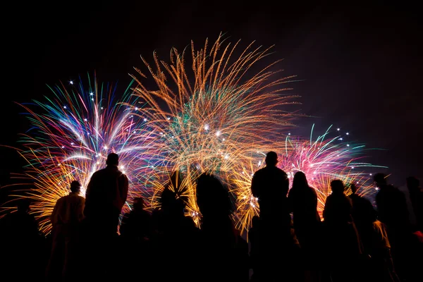 Grandes fuegos artificiales con siluetas de gente mirándolo — Foto de Stock