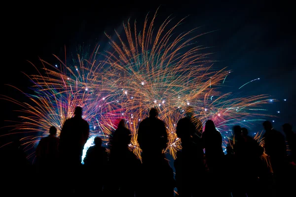 Grandes fogos de artifício com silhuetas de pessoas assistindo — Fotografia de Stock