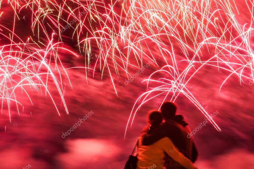 Big fireworks with young romantic couple in love in front, holdi