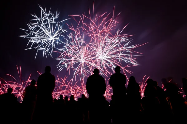 Grands feux d'artifice avec des gens silhouettes au premier plan regarder — Photo